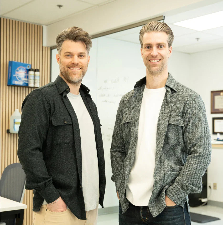 Two men standing in modern office near HVAC cleaning products and whiteboard